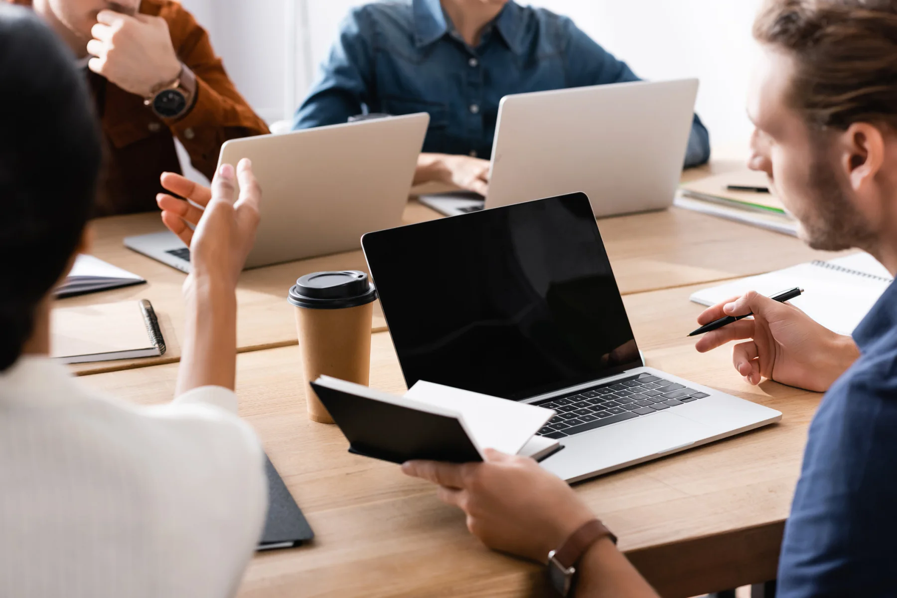 Enterprise project team working in a modern office with laptops and large displays
