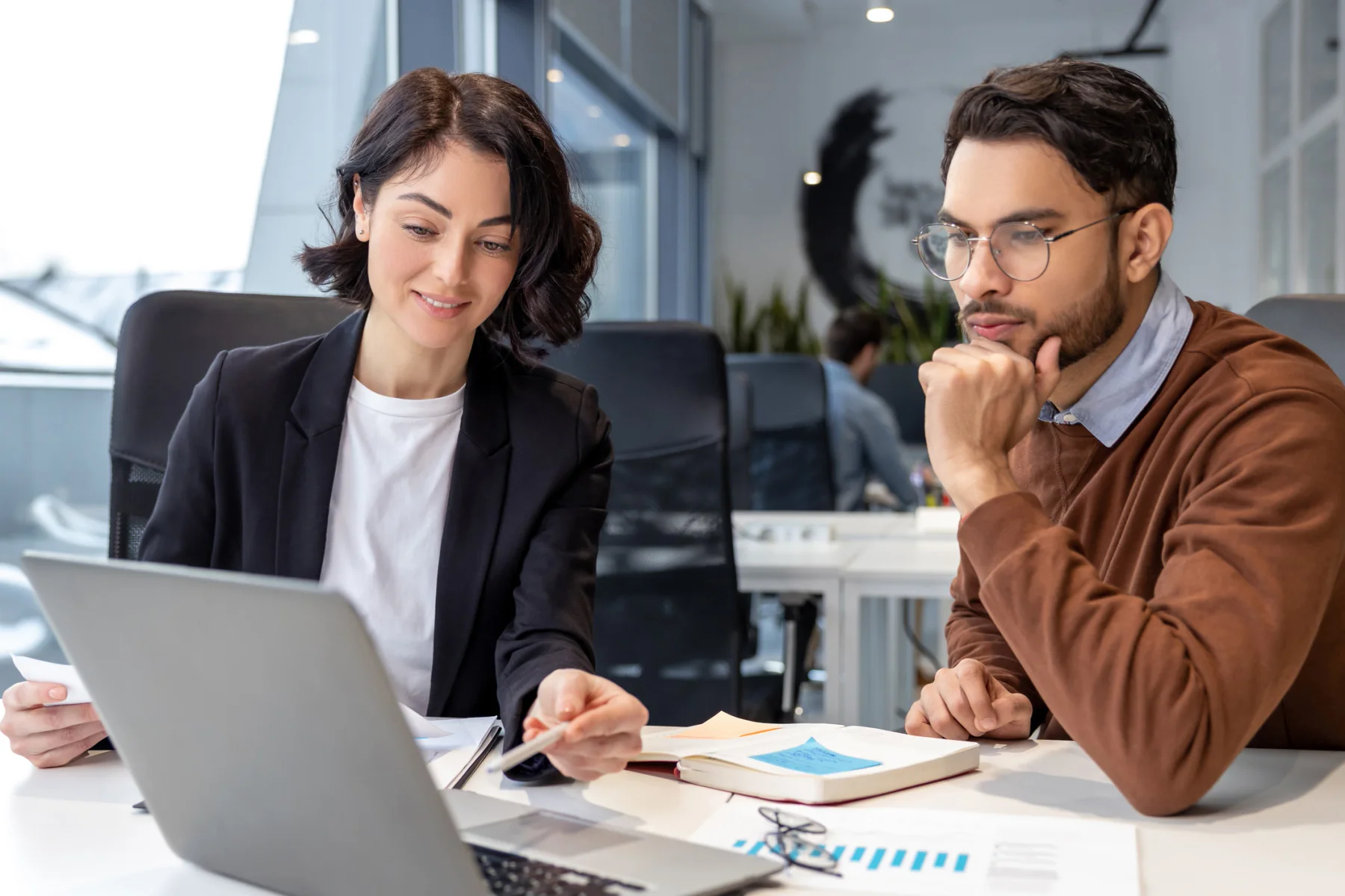 Financial professionals working on laptops and dual monitors in a modern office
