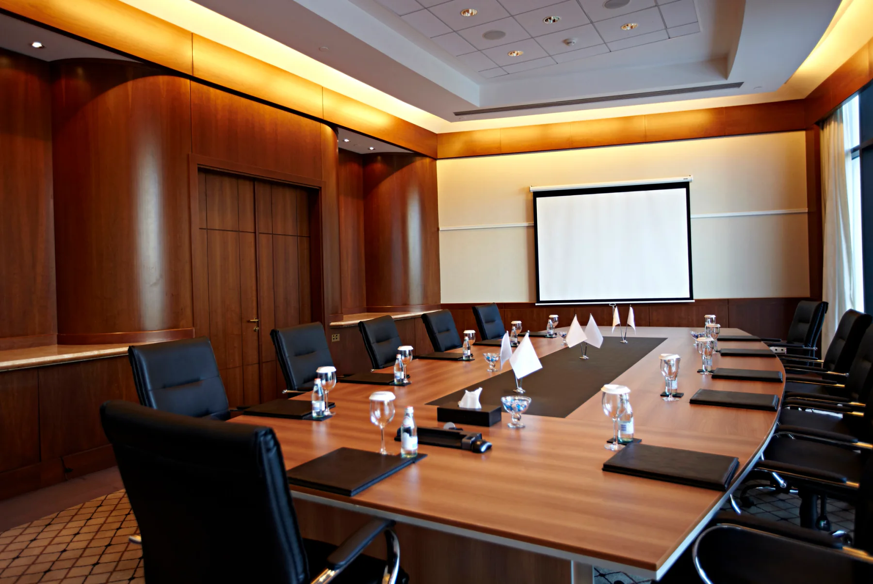 Corporate meeting room with rental display, presenter laptop, microphones, and professional technology setup for executive presentations