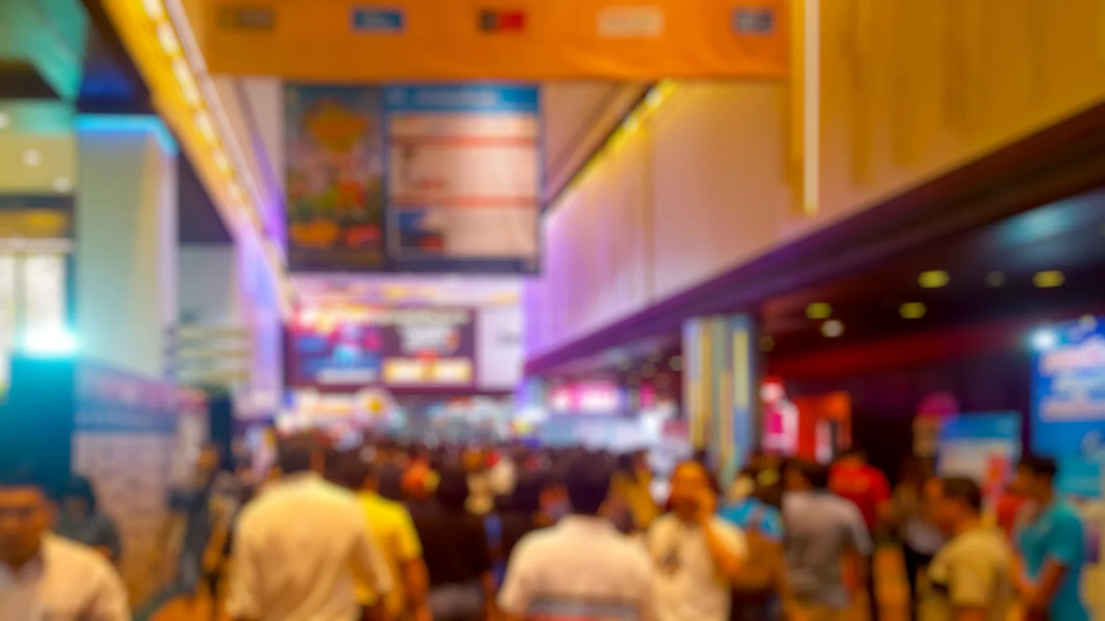 Large digital signage displays on a trade show floor showing event information sponsor messaging and booth content