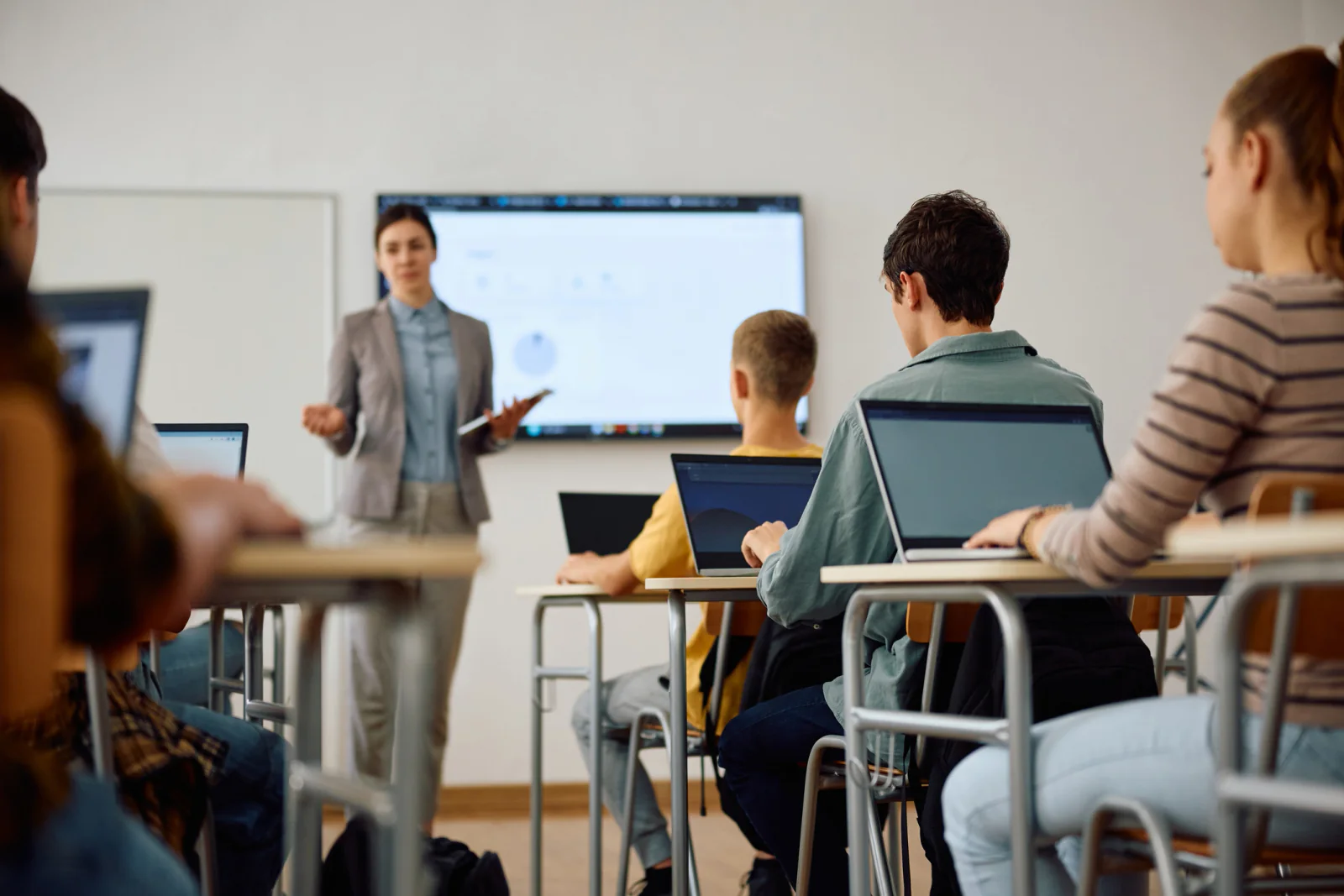 Educators in a training room using laptops and a projector during a district curriculum rollout session
