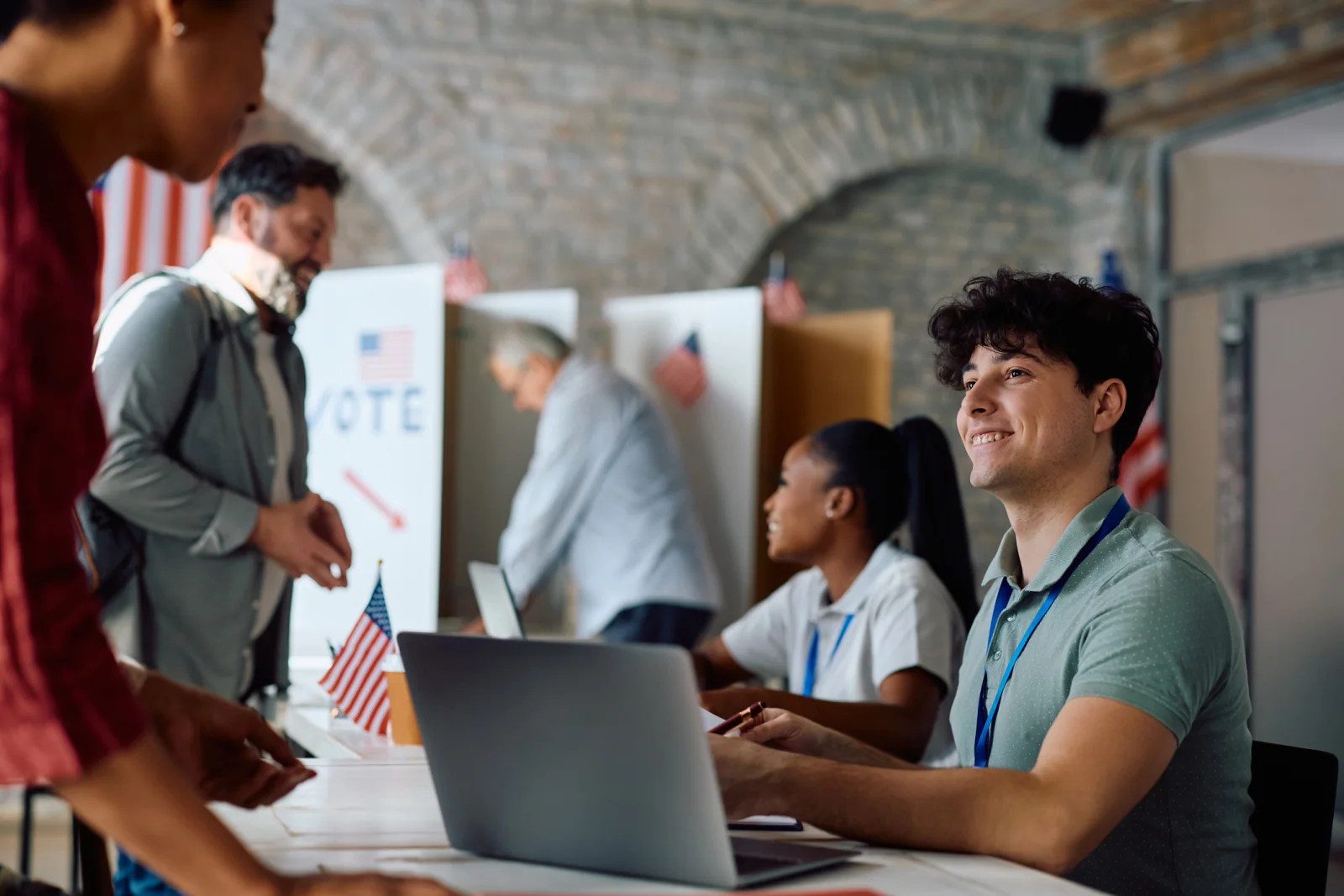 Campaign rally setup with registration tables, sound system, projection screens, and event staff preparing for attendees