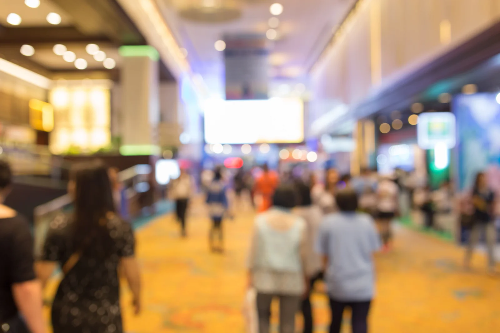 Large convention center conference with registration counters, digital signage, breakout rooms, and attendees moving through the venue