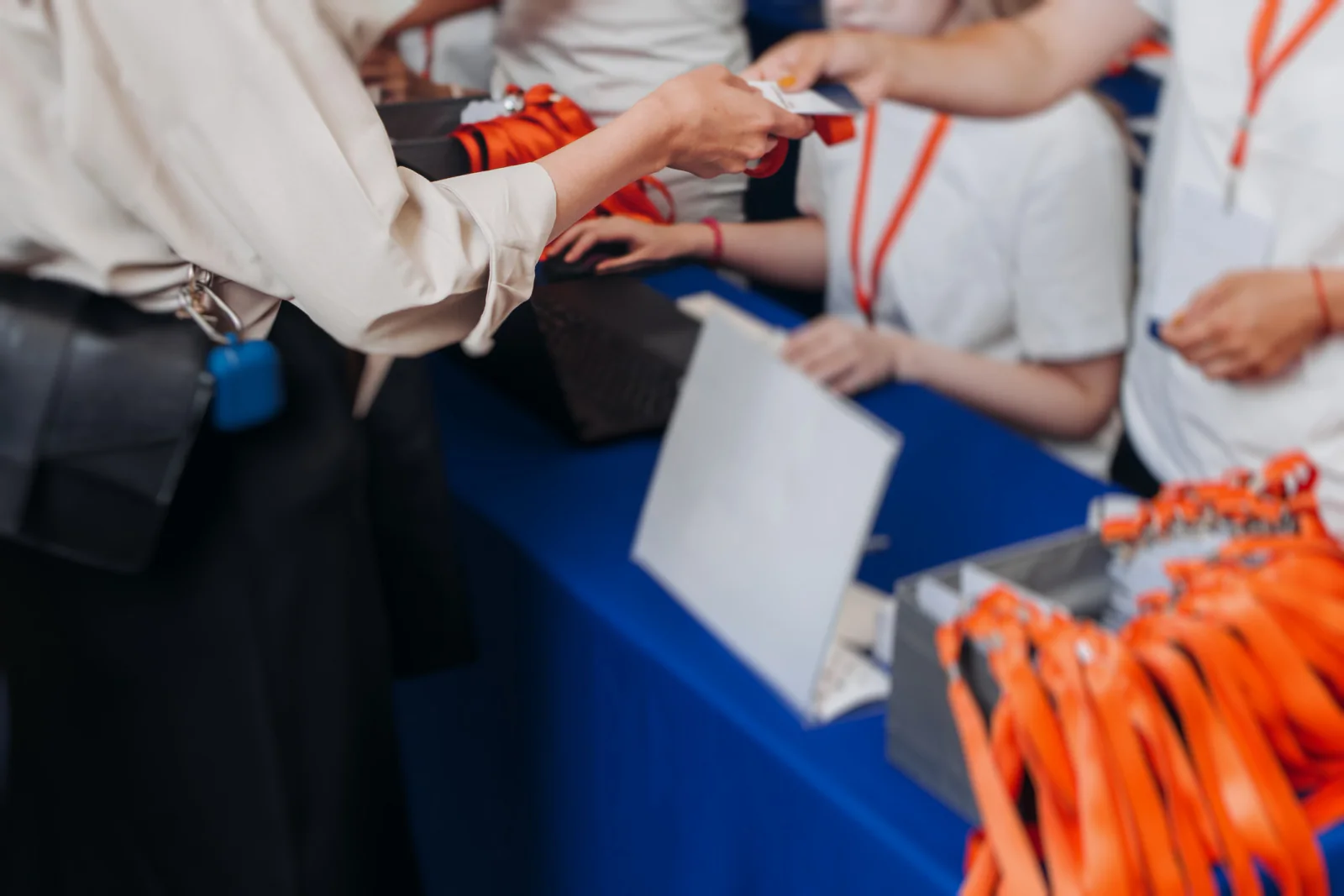 Event registration check-in tables with rental tablets, charging accessories, and staff processing attendee arrivals at a live event