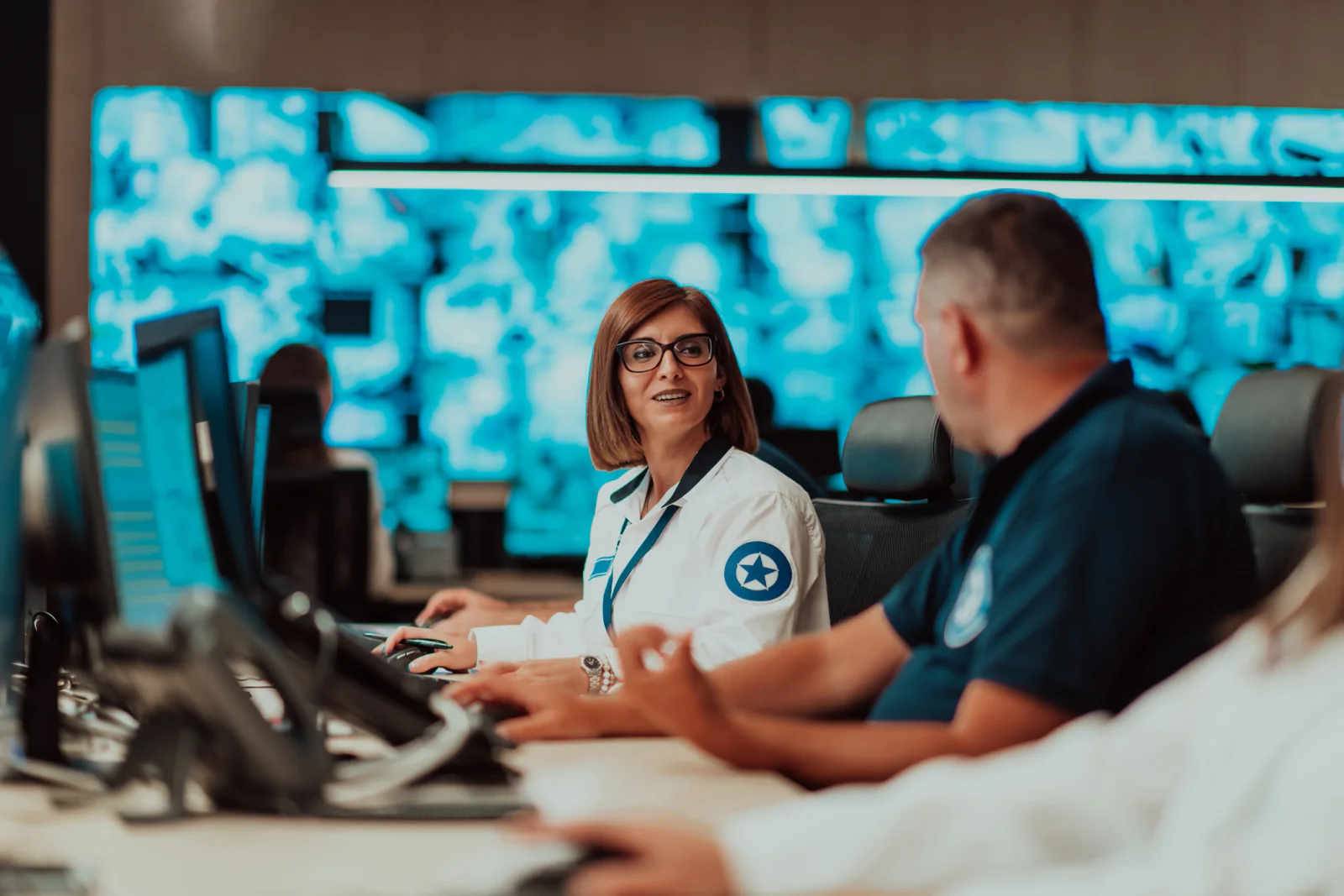 Hospital incident command center with staff at workstations and multiple large displays tracking emergency operations