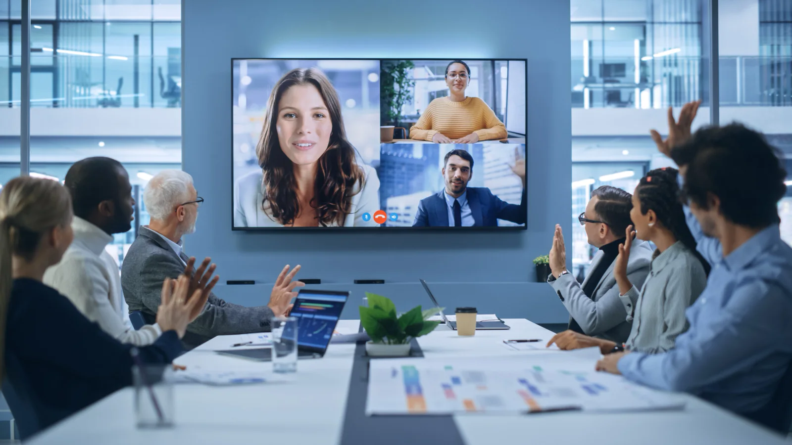 Board or committee meeting with in-person attendees, remote participants on displays, and hybrid meeting AV equipment