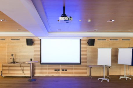 A wall mounted projector screen and two portable projector screens