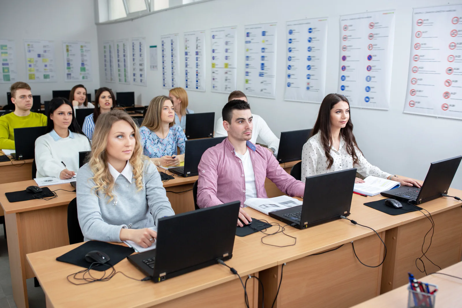 Classroom training room with rows of standardized rental laptops, chargers, and accessories prepared for a corporate learning session