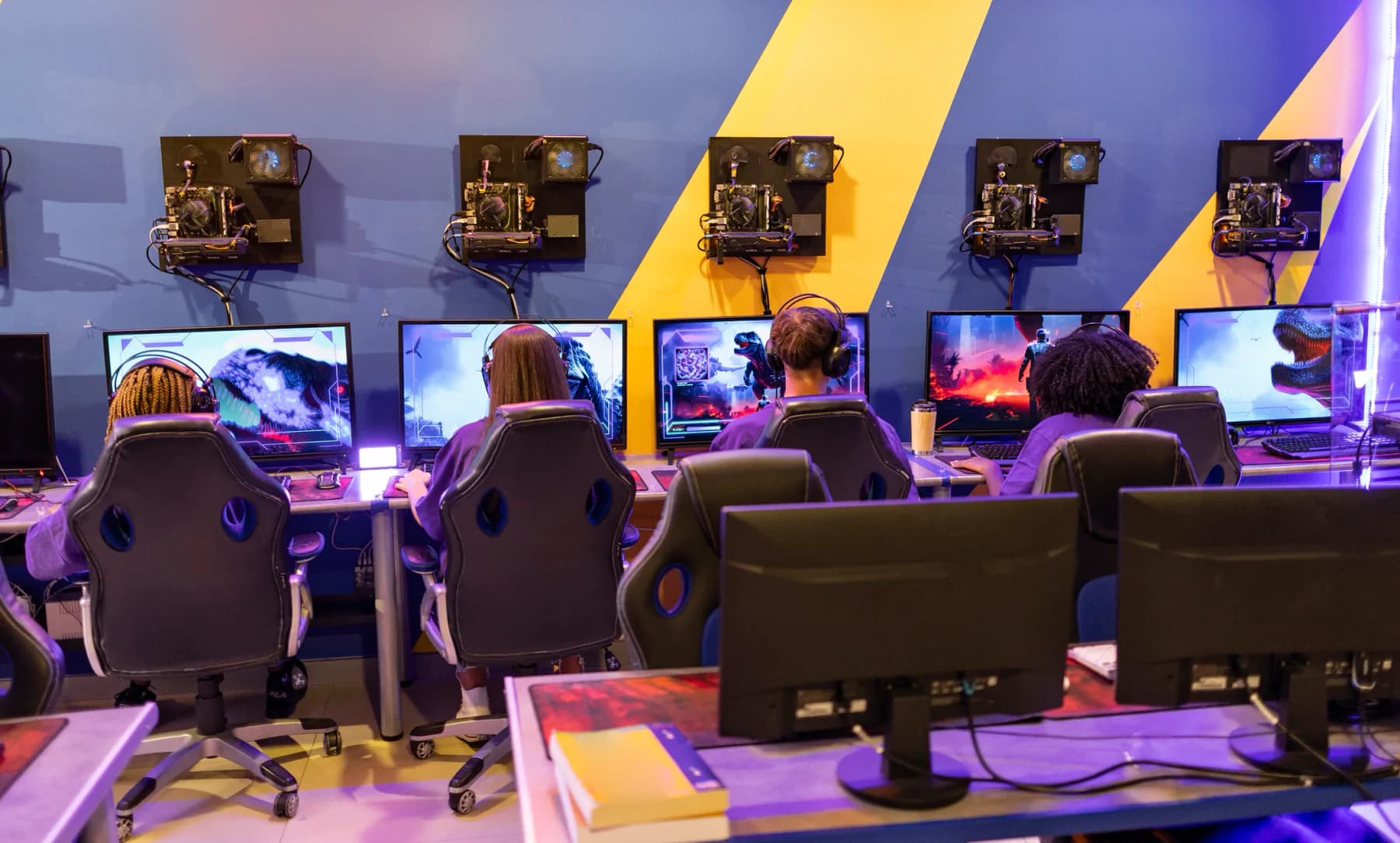 Large esports tournament floor with rows of gaming PCs, gaming monitors, stage lighting, and event staff supporting live competition
