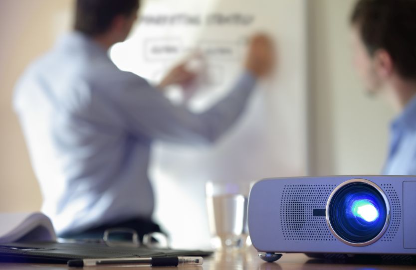 A projector sitting on a conference room table.