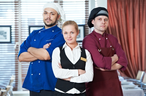 2 chefs and a hostess stand with their arms crossed