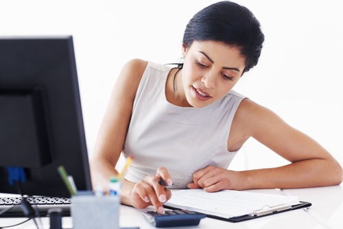 A woman sitting at a desk using a calculator