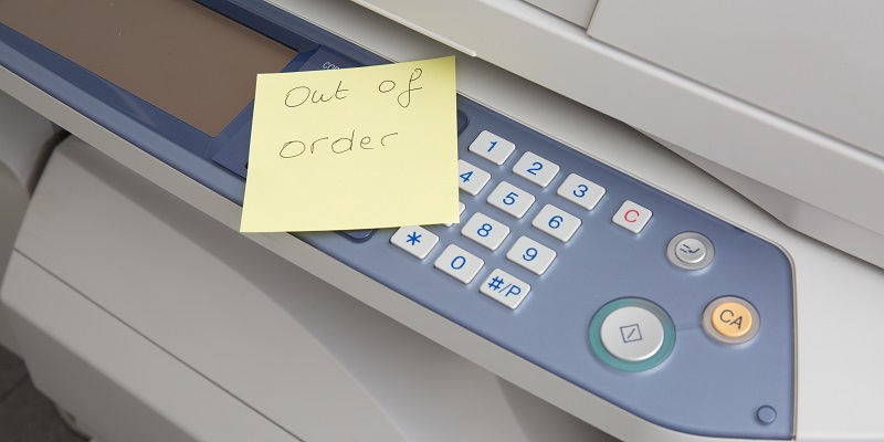 A copy machine with a note on it stating that the machine is out of order