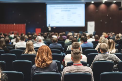 A crowd in an auditorium watching a presentation