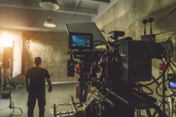 A man in front of a production camera on a film set