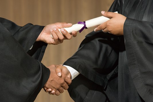 A diploma being handed to a graduate