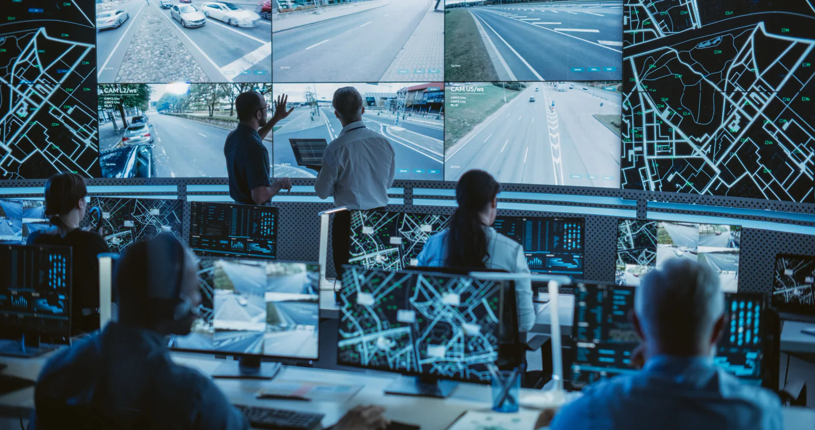 Telecommunications network operations center with operator workstations, multiple monitors, and large wallboard status displays during a peak operations period
