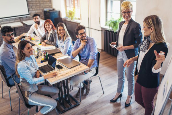 A group of employees around a small conference table watching a presentation being given