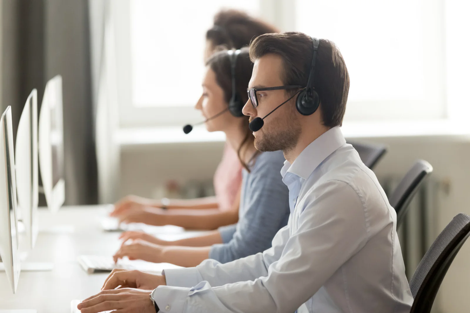 Temporary contact center with staff working at phones and dual-monitor computer stations during continuity operations