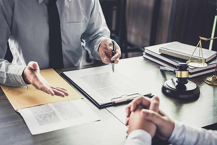 Two individuals across each other from a desk discussing legal documents