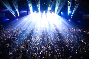 A large crowd of people all facing a lit stage