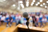 A podium with a microphone and a crowd of people waiting to listen