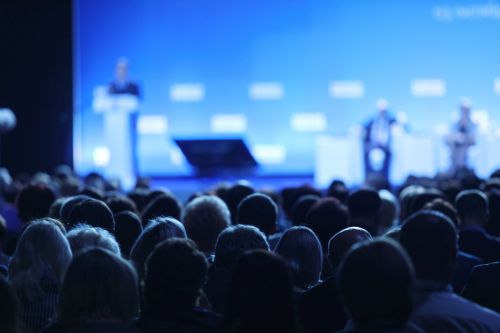 A full auditorium watching a product release event on stage