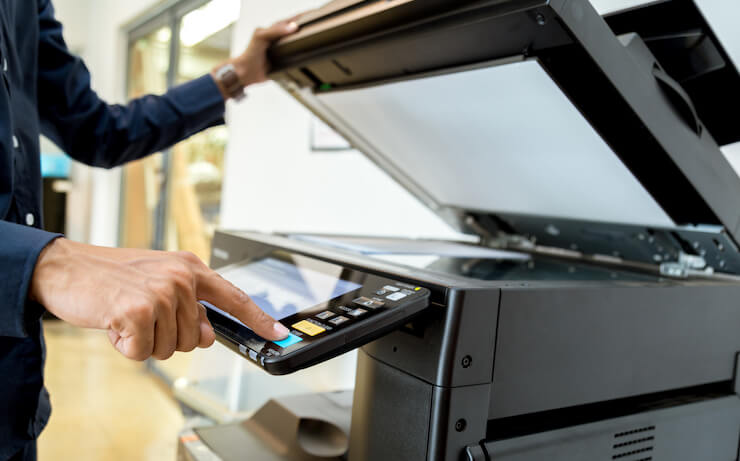 A flatbed copier with the lid open and an individual starting the copying process