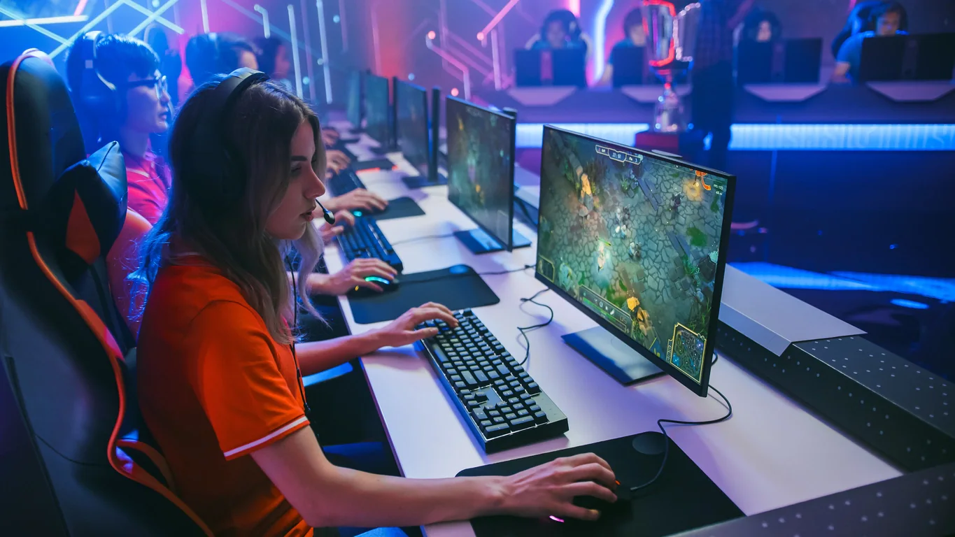 Esports tournament player stations with rows of gaming PCs, gaming monitors, keyboards, mice, and competition desks