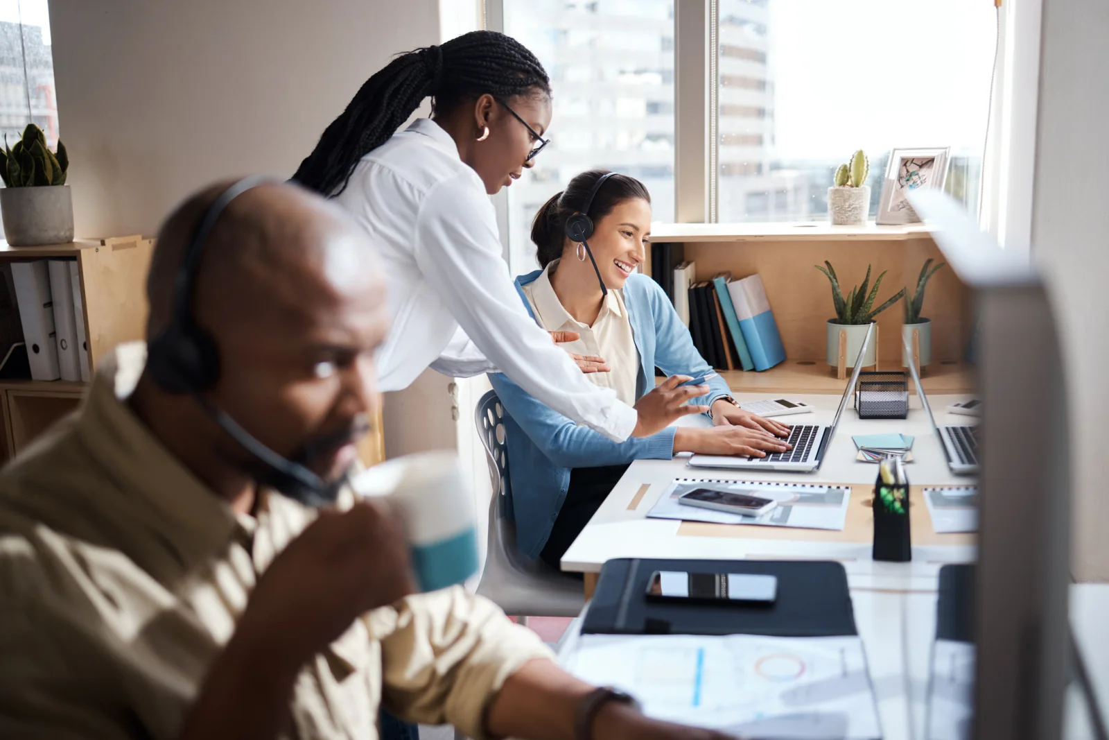 Business team planning cloud calling and collaboration workflows with laptops, headsets, and remote communication tools in an office meeting