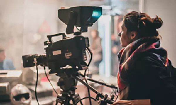 A woman looking through the viewfinder of a production camera