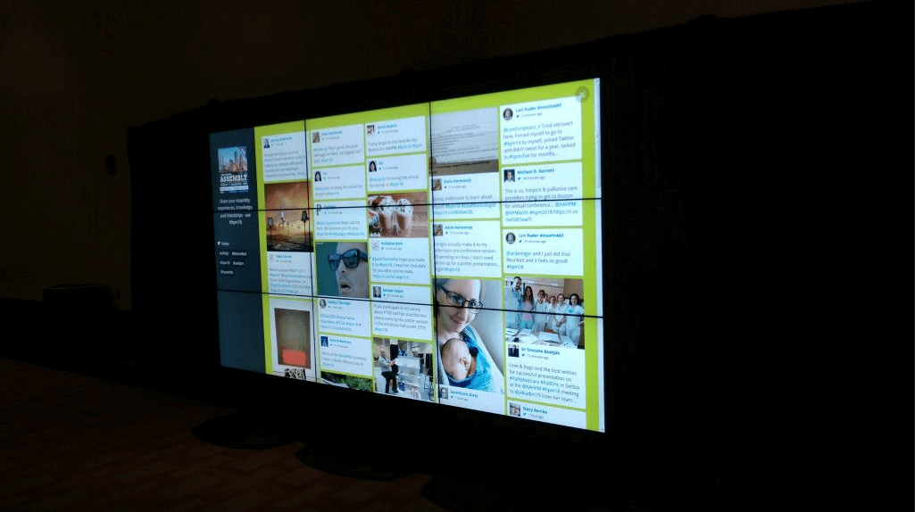 A video wall composing of 9 total screens being used as a social media wall, displaying various social media posts